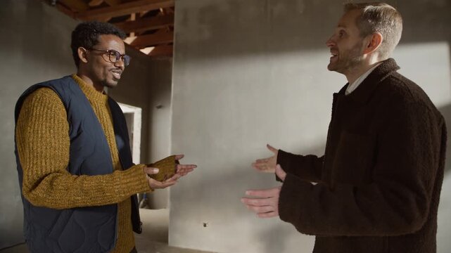 Diverse designer and client shaking hands at active construction site, finalizing design plans and celebrating agreement on project details and next steps