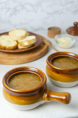 The process of cooking French onion soup. Two ceramic bowls with soup. Traditional cuisine concept. Vertical orientation. Selective focus.