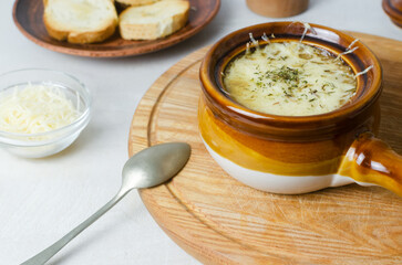The process of cooking French onion soup. Ceramic bowls with soup and melted cheese and a spoon. Traditional cuisine concept. Horizontal orientation. Selective focus.