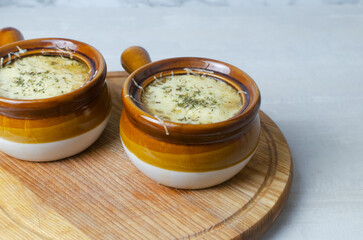 The process of cooking French onion soup. Two ceramic bowls with soup and melted cheese. Traditional cuisine concept. Horizontal orientation. Selective focus.
