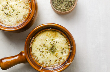 The process of cooking French onion soup. Two ceramic bowls with soup, melted cheese and dried thyme. Traditional cuisine concept. Horizontal orientation. Selective focus. Top view. Copy space