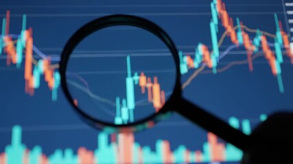 A magnifying glass is held over a vibrant stock market chart displayed on a blue screen, highlighting red and green candlesticks, representing business finance and investment analysis. - Powered by Adobe