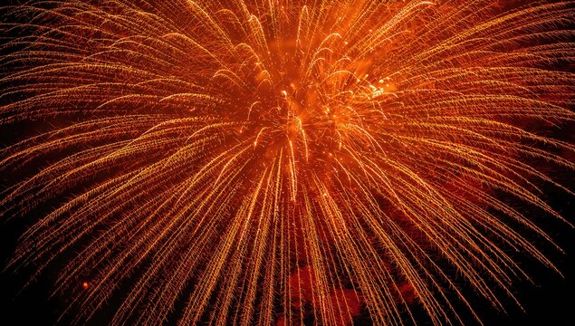 Vibrant golden orange fireworks burst against a dark backdrop, celebration of Independence Day