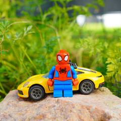 Obraz premium Spider-Man Lego figure with a yellow sports car on a rock