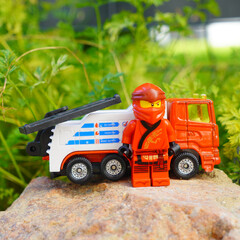 Obraz premium Lego Ninjago figure stands next to a toy tow truck on a rock