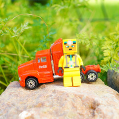 Naklejka premium Minecraft character stands next to a red Coca-Cola semi-truck toy