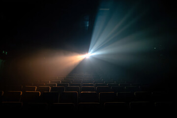 Dramatic theater scene with a projector light shining over empty seats.