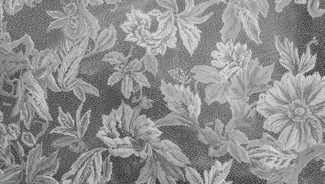 A delicately designed gray lace fabric featuring intricate floral patterns and elaborate detailing, ideal for luxurious textile applications.