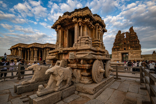 Hampi, India - 01 November 2025: View of the intricately carved stone chariot at Vijaya Vitthala Temple stands majestically against a backdrop of ancient ruins and a vast sky.