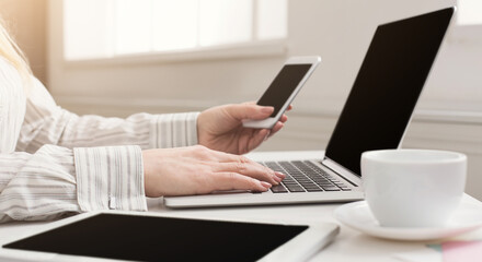 Woman manager working on laptop and holding phone