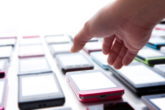 hand choosing smartphone from collection of mobile devices