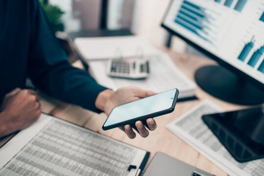 person using smartphone while analyzing financial data on computer