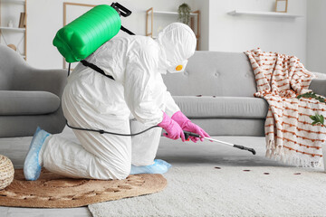 Male pest control specialist carrying out cockroach disinfection in room