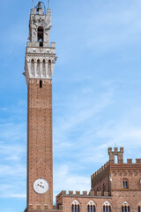 Obraz premium Siena cathedral tower rises majestically against a clear blue sky, showcasing intricate architectural details and ancient brickwork, inviting exploration and admiration of historical beauty