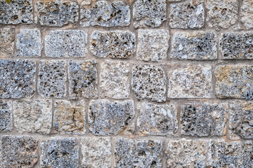 Durable stone wall featuring a unique pattern of textured blocks, showcasing a blend of gray and beige tones in an outdoor setting for functional design concepts