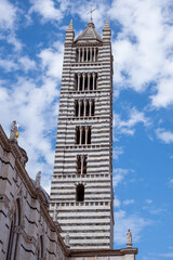 Obraz premium Striking bell tower In Siena, Italy with intricate stonework rises against a vibrant blue sky, showcasing architectural beauty and historical significance in a captivating sightseeing destination