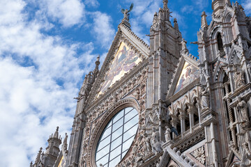 Obraz premium Majestic Siena cathedral in Italy, facade showcasing intricate architectural details under a bright blue sky, inviting travelers to explore ancient beauty and rich history with copy space
