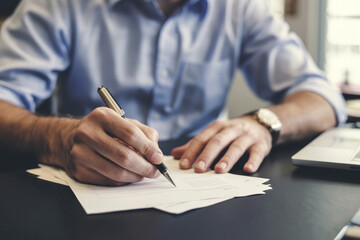 A businessman signs important documents.