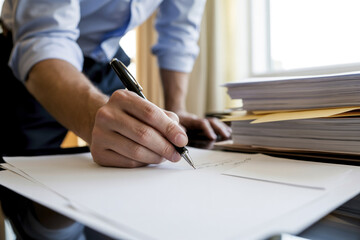 A businessman writes something on a sheet of paper.
