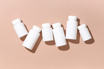 Many blank plastic vitamin bottles on brown background