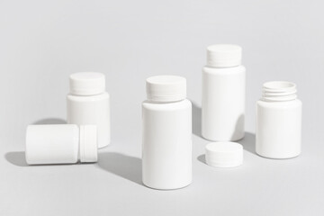 Many blank plastic vitamin bottles on grey background