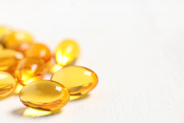 Vitamin E pills on white wooden background, closeup