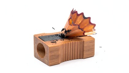 Pencil sharpener with shavings. Dark graphite dust and wooden peel is seen. Simple studio shot on white