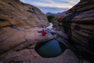 A lone traveler, a tourist in the canyon of Three wells. The mesmerizing beauty of the Bektau Ata Nature Park in Kazakhstan, where ancient rocks and calm waters create an atmosphere of peace.