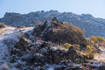 The first snow has covered the mountain peaks, but the autumn colors have not yet given up. Golden foliage against the background of snow-covered rocks creates an amazing contrast