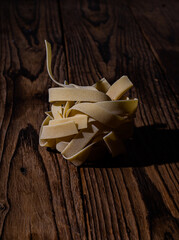 raw tagliatelle pasta nest arranged on dark wooden background, cooking ingredient