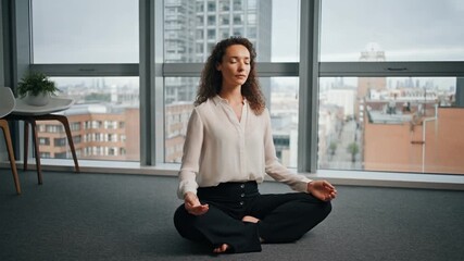 A woman meditating alone in a quiet empty meeting room with a city view during her lunch break. Integrating mindfulness and mental health practices into the workday. - Powered by Adobe