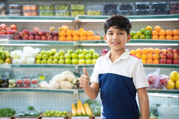 Indian little boy standing at fruits department at super shop