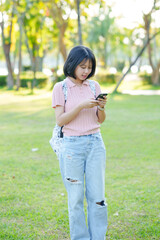 A young woman listens to music on her phone. An Asian woman stretches after sitting for a long time.
