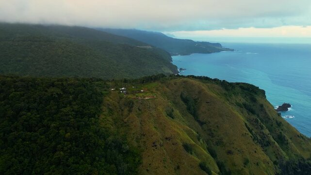 Closing‑in aerial of Dingalan Pacific View Deck, moving toward lush green hills and rugged cliffs as the dramatic coastline and turquoise sea come into fuller view.