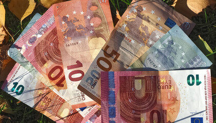 Financial situation of Europe in autumn - Euro banknotes with fallen autumn leaves