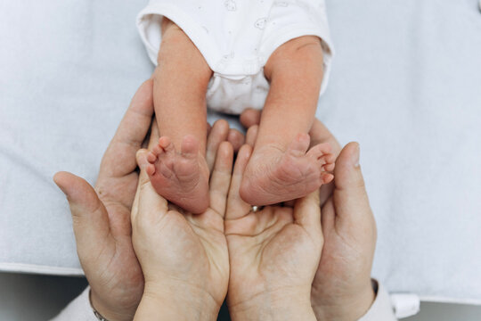 Newborn baby feet in parents hands symbolizing love, care and family protection