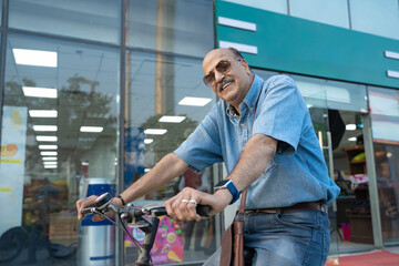 Fototapeta premium Indian senior man riding bicycle on city street.