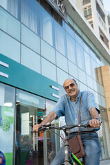Fototapeta premium Indian senior man riding bicycle on city street.