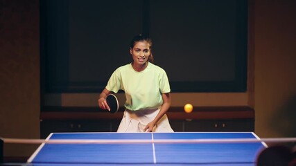Indian happy young adult gen z player woman hold racket play table tennis pool male man pass ball indoor dark room Asian sporty girl lady do sports training enjoy ping pong learn game have fun joy day - Powered by Adobe