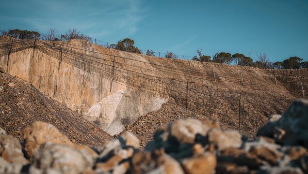 Cliff secured with metal netting to avert rock falls and landslides, erosion risk