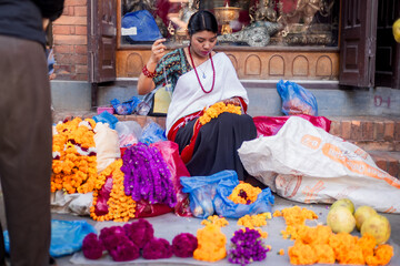 Newari Girl in traditional attire Crafting Globe Amaranth Garlands(makhmali flower) for Bhai Tika in tihar
