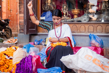 Newari Girl in traditional attire Crafting Globe Amaranth Garlands(makhmali flower) for Bhai Tika in tihar