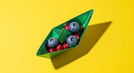 Origami Boat with Berries on Yellow Background