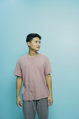 Pensive young man looking sideways against serene blue background, ideal for introspective campaigns or youth-focused marketing, modern style and simple