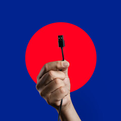 Hand holding a black USB-A cable on a graphic blue and red background.
