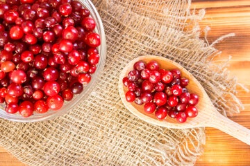 Ripe organic cranberries on rustic wooden table. Autumn harvest and healthy nutrition concept. Natural red berries background for seasonal design, countryside lifestyle and eco food theme.
