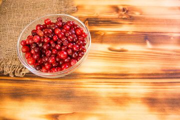 Ripe organic cranberries on rustic wooden table. Autumn harvest and healthy nutrition concept. Natural red berries background for seasonal design, countryside lifestyle and eco food theme.