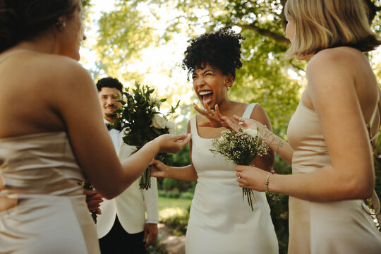 Bride celebrating joyous wedding moment with bridesmaids and nature backdrop