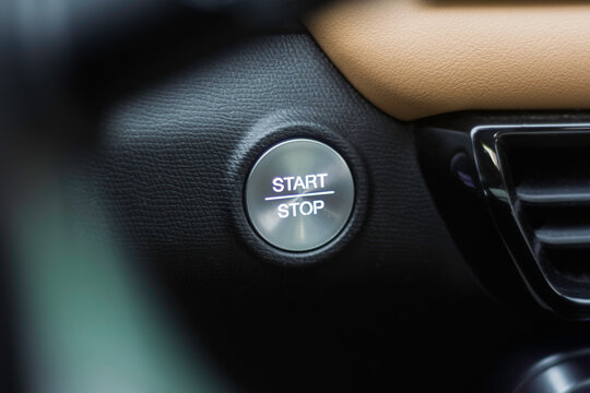 Car interior with illuminated start stop button set in textured leather dashboard, signaling readiness for urban commute or road trip.