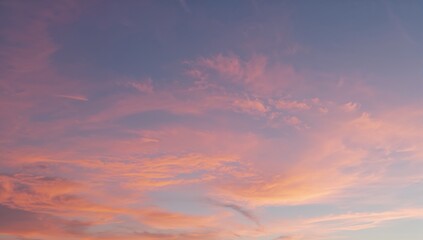 Obraz premium A tranquil sky at sunset adorned with delicate clouds in soft shades of pink, orange, and blue, evoking a peaceful transition to evening